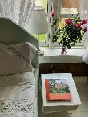a bed with a book on a table next to a window at Historic Farm With Sea View Over Bjørnefjorden