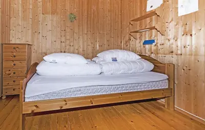 a bed in a wooden room with white pillows at Stunning Home In Steinstø With Wifi in Steinstø