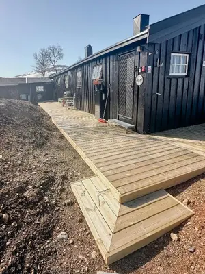 a wooden deck next to a building with a basketball hoop at Idyllic Cabin By The Water In Hessdalen in Ålen