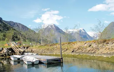 a couple of boats docked on a river with mountains at Stunning Home In Fjærland in Fjarland