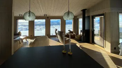 a living room with a table and chairs and windows at Family Cabin With Picturesque View At Røn in Ron