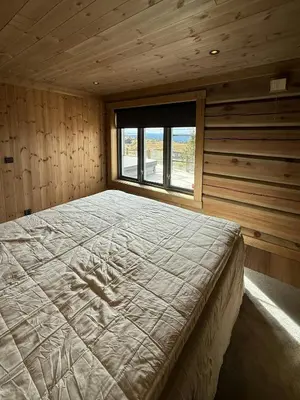 a large bed in a wooden room with a window at Luxurious Log Cabin At Mostertoppen in Øyer