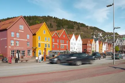 a city with cars driving down a street with buildings at Bergen Beds Apartment I 100 meters from Bryggen! in Bergen