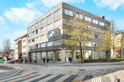 a building on a street with people walking in front of it at Bergen Beds Apartment I 100 meters from Bryggen! in Bergen