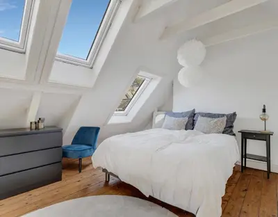 a bedroom with a white bed and a blue chair at Classic Bergen apartment peaceful space in the city center in Bergen