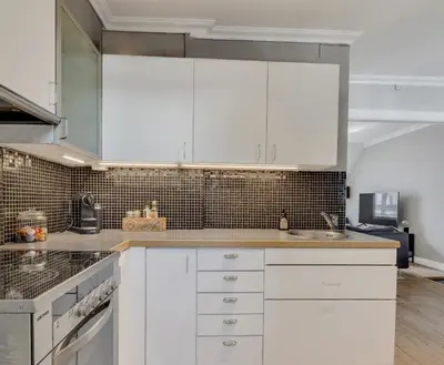 a kitchen with white cabinets and a sink at Classic Bergen apartment peaceful space in the city center in Bergen