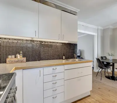 a white kitchen with white cabinets and a table at Classic Bergen apartment peaceful space in the city center in Bergen