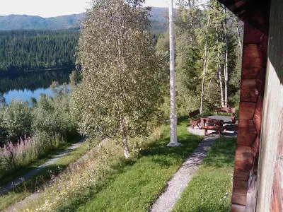 a bench on the side of a house next to a lake at Gravraakstuggu in Storneve
