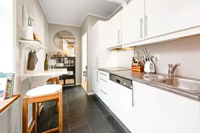 a kitchen with white cabinets and a sink at Bright City Apartment - Perfect Central Stay in Bergen