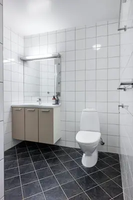 a white bathroom with a toilet and a sink at Bright City Apartment - Perfect Central Stay in Bergen