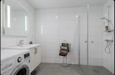 a white bathroom with a washing machine and a shower at Modern three-room apartment, private terrace and roof terrace in Trondheim