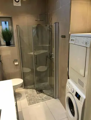 a bathroom with a shower and a washing machine at Moderne Leilighet midt i Bykjernen in Bergen