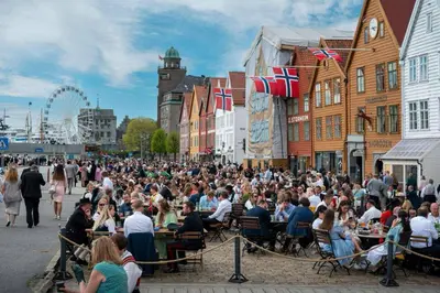 a crowd of people sitting at tables on a city street at Moderne Leilighet midt i Bykjernen in Bergen