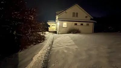 a snow covered driveway with a garage at night at Landlige Peru in Ringsaker