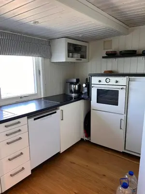 a small kitchen with white appliances and a window at En Perle ved Masfjorden in Masfjorden