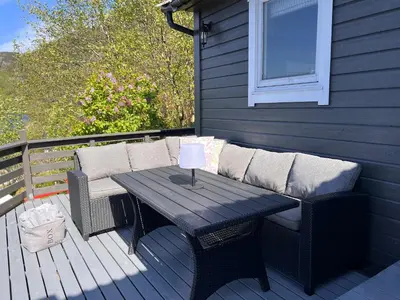 a patio with a table and chairs on a deck at En Perle ved Masfjorden in Masfjorden