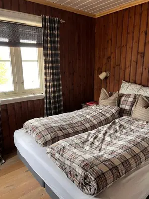 two beds in a room with wood paneled walls at Drøm deg bort til fjells Velkommen til en perle av en hytte in Masfjorden