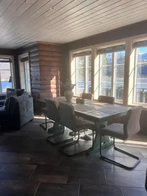 a dining room with a table and chairs and windows at Drøm deg bort til fjells Velkommen til en perle av en hytte in Masfjorden