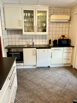 a kitchen with white cabinets and a tile floor at Faleide Grandview in Stryn