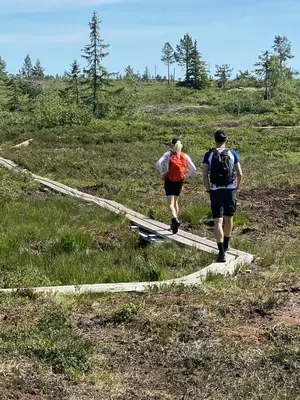 two people walking on a trail in a field at Modern Light Neo Cabin On Bjefell in Svene