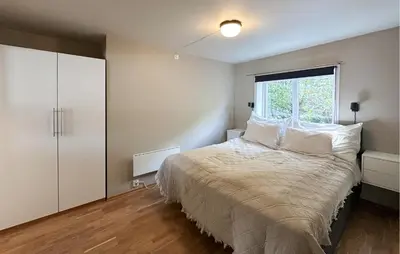 a bedroom with a bed with white pillows and a window at 2 Bedroom Cozy Apartment In Laksevåg in Bergen