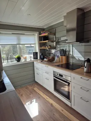 a kitchen with white cabinets and a large window at Feriebolig Fannrem in Torshus