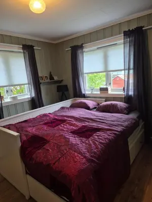 a bedroom with a large bed with purple sheets and windows at Feriebolig Fannrem in Torshus