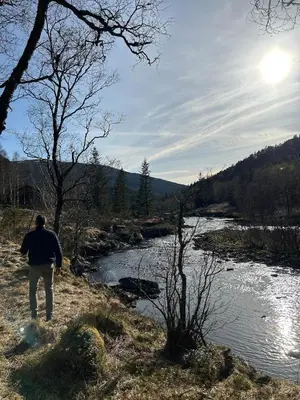 a man is standing next to a river at Cozy cabin in Eikedalen in Eikedalen