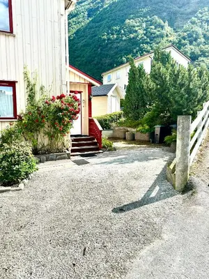 a house with a white fence and a mountain at FjordNest Årdalstangen in Årdalstangen