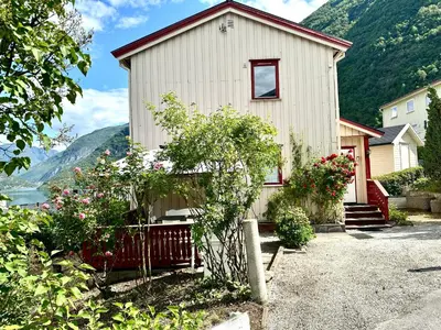 a white house with mountains in the background at FjordNest Årdalstangen in Årdalstangen