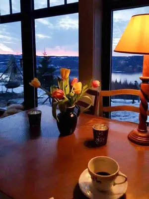 a table with a vase of flowers on a table with a window at Private Cabin With Stunning Views Near Oslo in Eina