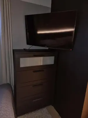 a bedroom with a dresser with a flat screen tv at Modern semi-detached house with free parking in Lillehammer