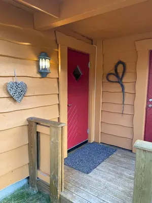 a red door on the side of a house at Adventurous cabin cozy on Sjusjøen with sauna! in Sjusjøen