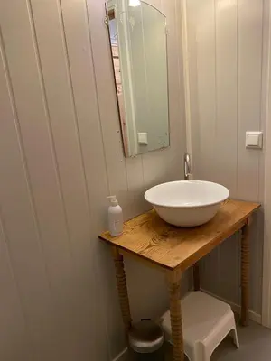 a bathroom with a white sink and a mirror at Seaside apartment in farmhouse close to nature in Husevåg