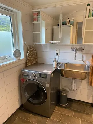 a small kitchen with a washing machine and a sink at Seaside apartment in farmhouse close to nature in Husevåg