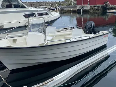 a white boat tied to a dock in the water at Seaside apartment in farmhouse close to nature in Husevåg