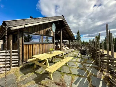 a wooden cabin with a picnic table in front of it at Modern mountain cabin Ski in-out 2 Bathrooms in Ringsaker