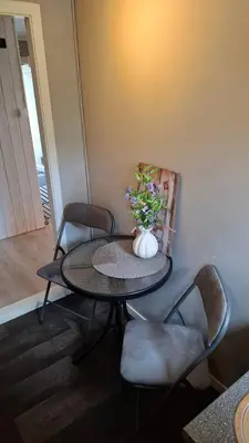 a table with chairs and a vase with flowers on it at Apartment in the heart of Sunnmore in Vigra