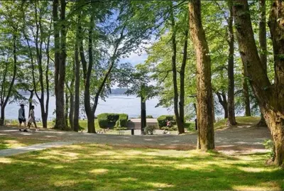 two people walking down a path in a park with trees at Rålekker 2-roms leilighet in Bergen