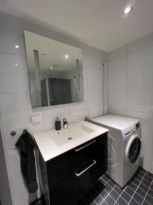 a bathroom with a washing machine and a sink at Staymate apartment at Lade in Trondheim
