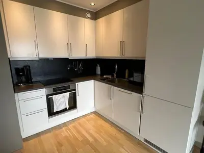 a kitchen with white cabinets and a sink at Staymate apartment at Lade in Trondheim