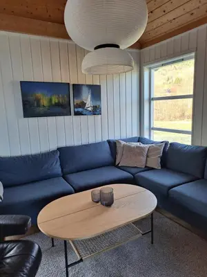 a living room with a blue couch and a coffee table at Stort hus med havutsikt ved fjord og fjell med båt in Lensvik
