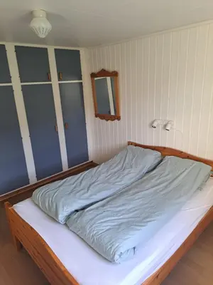 a bedroom with a large bed with a white sheets at Stort hus med havutsikt ved fjord og fjell med båt in Lensvik