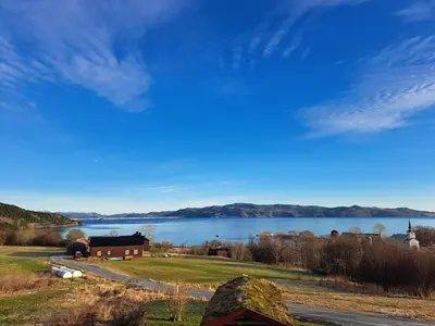 a view of a lake with a barn and a house at Stort hus med havutsikt ved fjord og fjell med båt in Lensvik