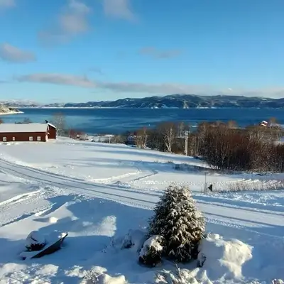 Stort hus med havutsikt ved fjord og fjell med båt
