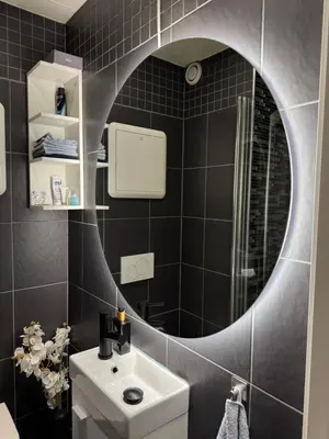 a bathroom with a round mirror and a sink at CozyStay Beside Historic Bryggen in Bergen