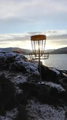 a frisbee golf basket on the edge of the water at Fjordgløtt in Blålia