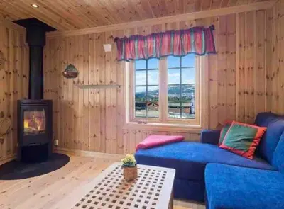 a living room with a blue couch and a fireplace at Trollslottet på Skeikampen in Aulstad