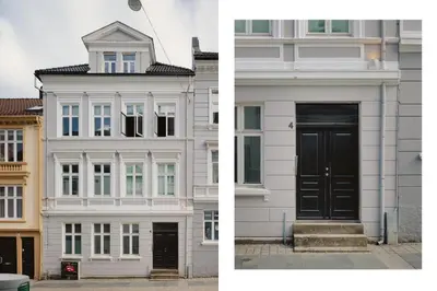 a white building with a black door on the side at Bergen City Living in Bergen