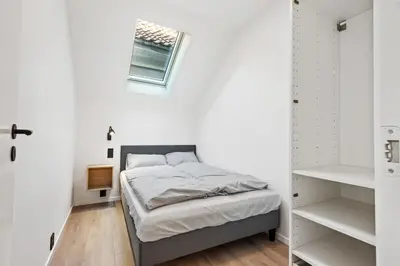 a bedroom with a bed with white walls and a window at Newly renovated apartment in the heart of Bergen city center in Bergen